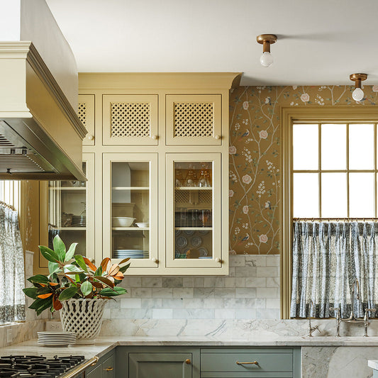 Modern kitchen with green and beige cabinets, marble countertop, and decorative elements.