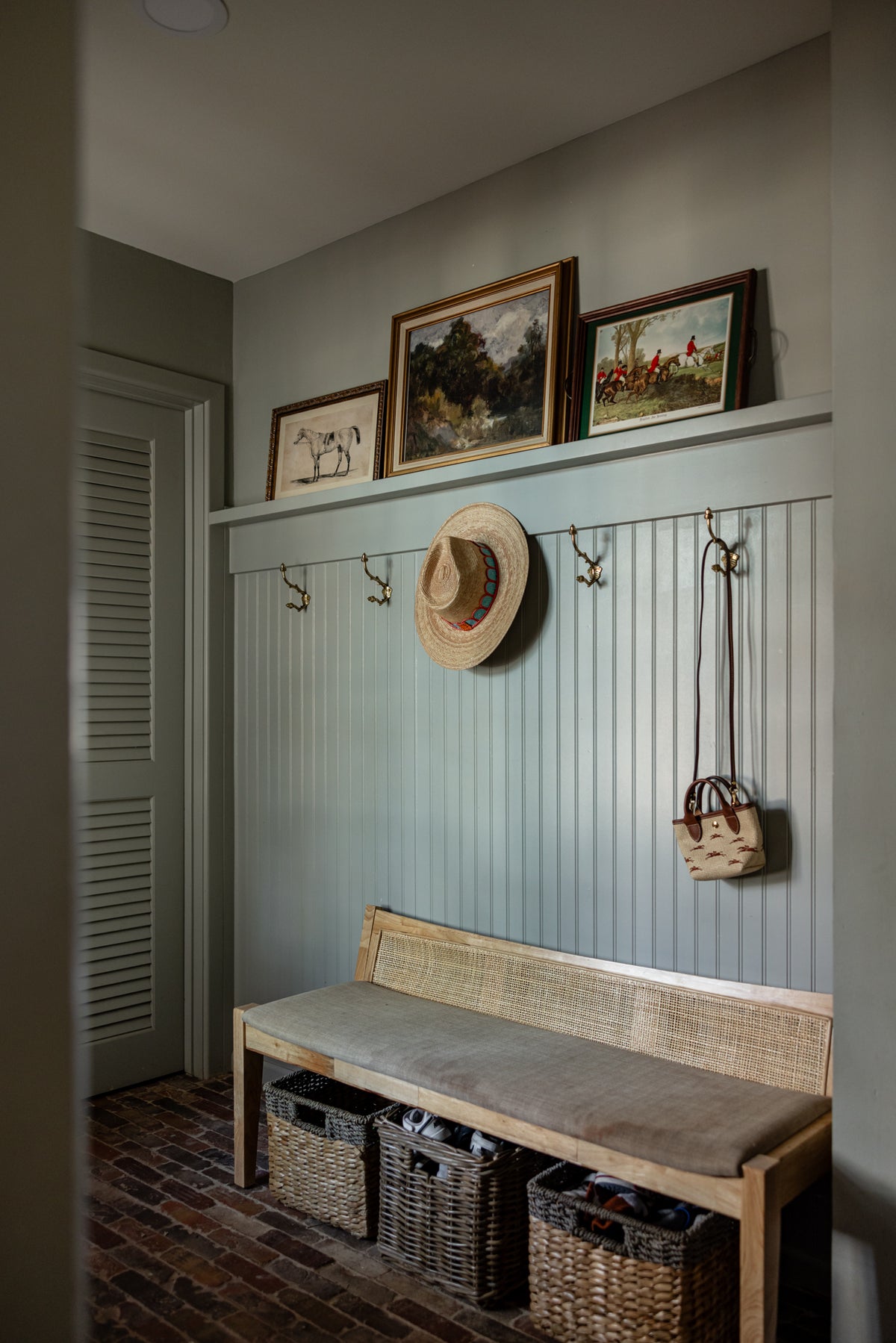 Mudroom with panelled walls, a cane bench and hunting prints