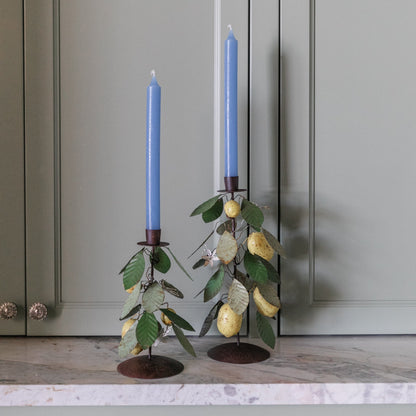 Two blue candles in decorative candle holders on a countertop with gray cabinets in the background.