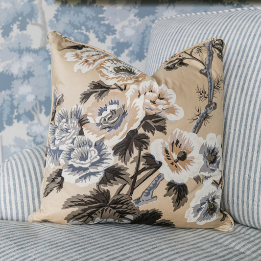 Floral-patterned pillow on a striped sofa with a decorative wall mirror in the background
