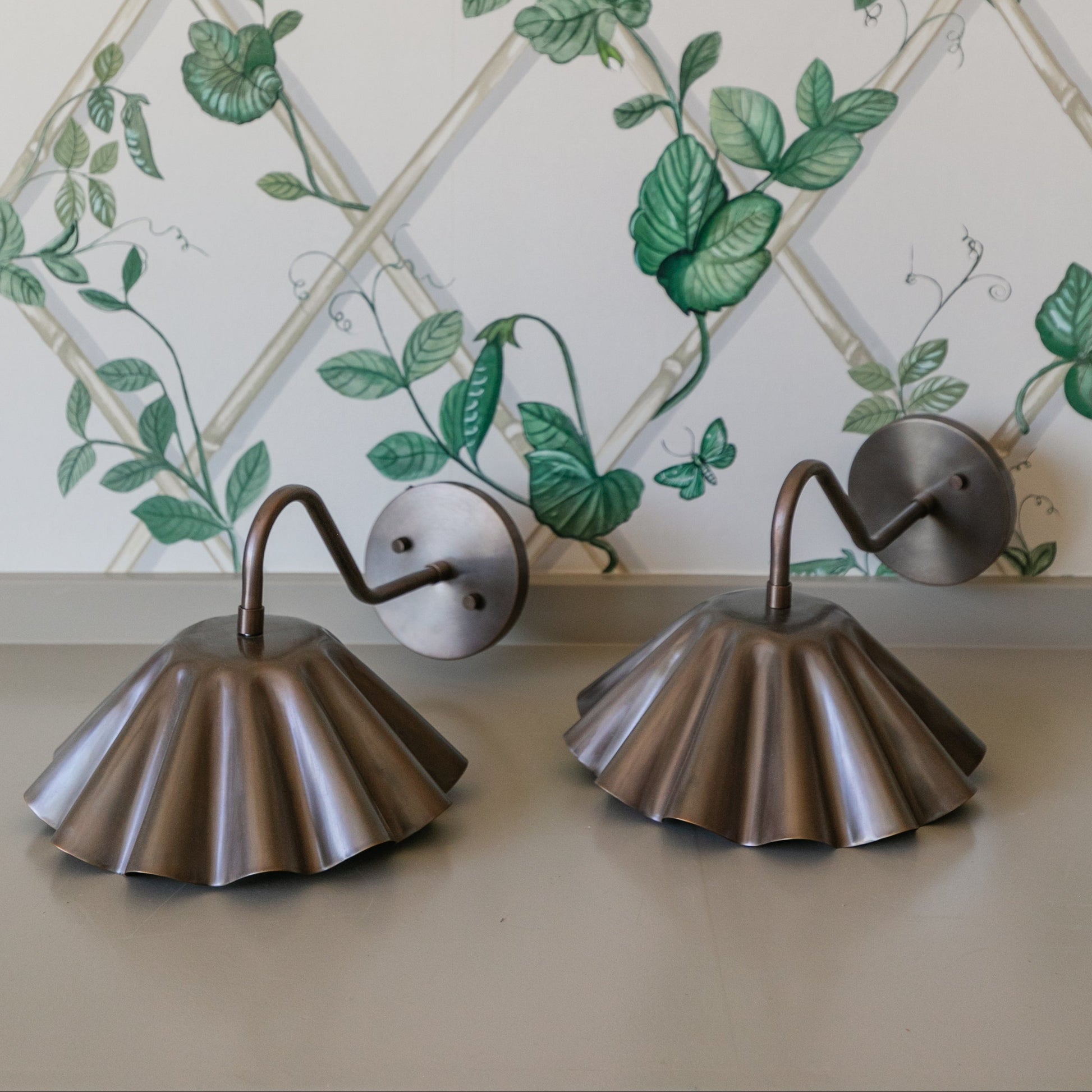 Decorative wall sconces against a floral wallpapered wall