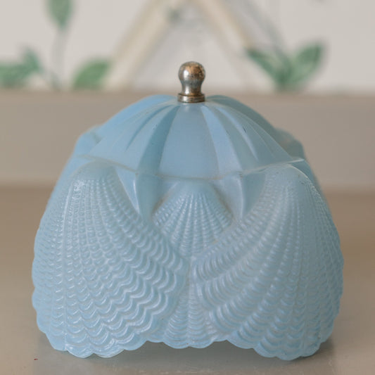 Blue textured container with a metallic cap on a light background
