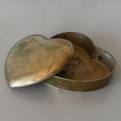 Heart-shaped brass box on a light gray background