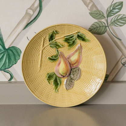 Decorative plate with fruit design on a wall with floral wallpaper