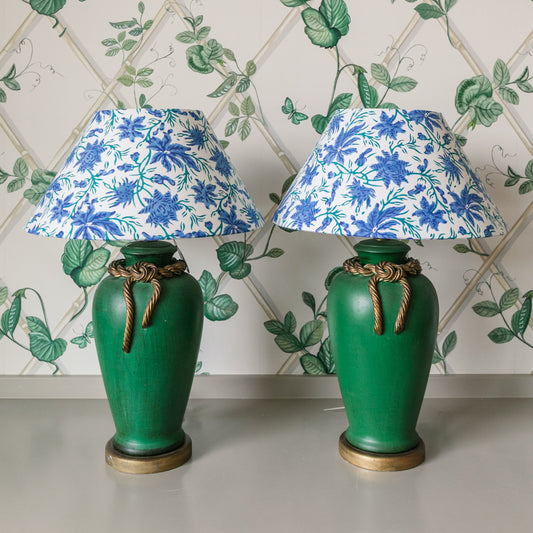 Two green lamps with floral lampshades against a decorative wallpaper background.