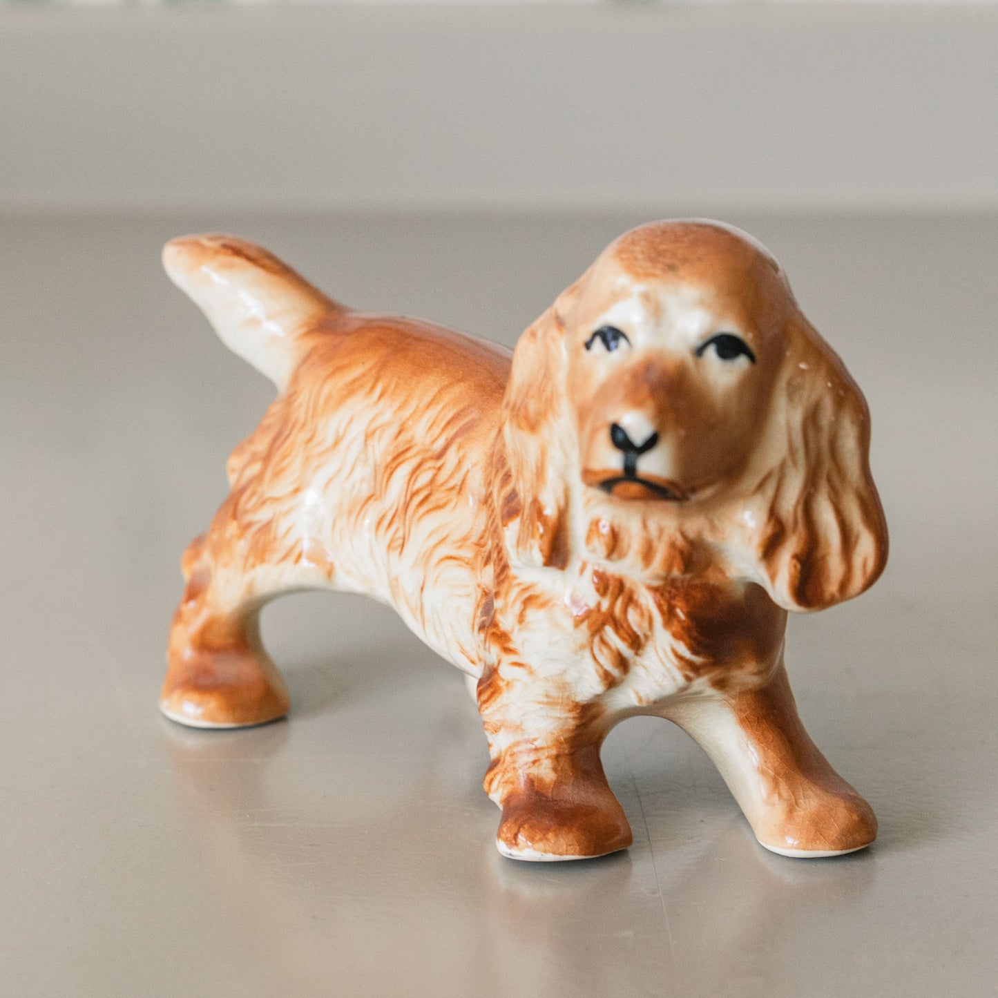 Ceramic dog figurine on a neutral surface with a blurred background