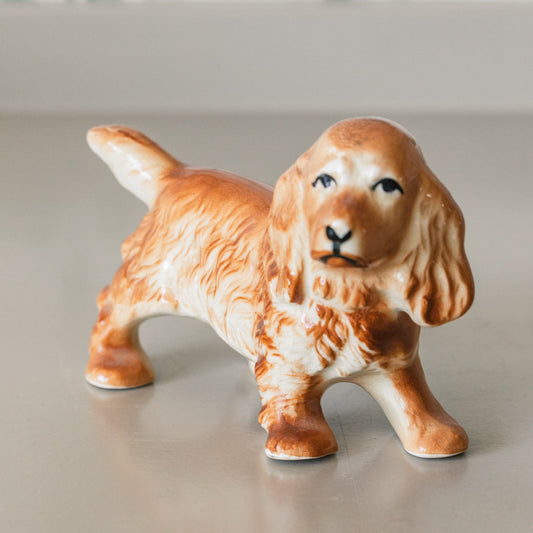 Ceramic dog figurine on a neutral surface with a blurred background
