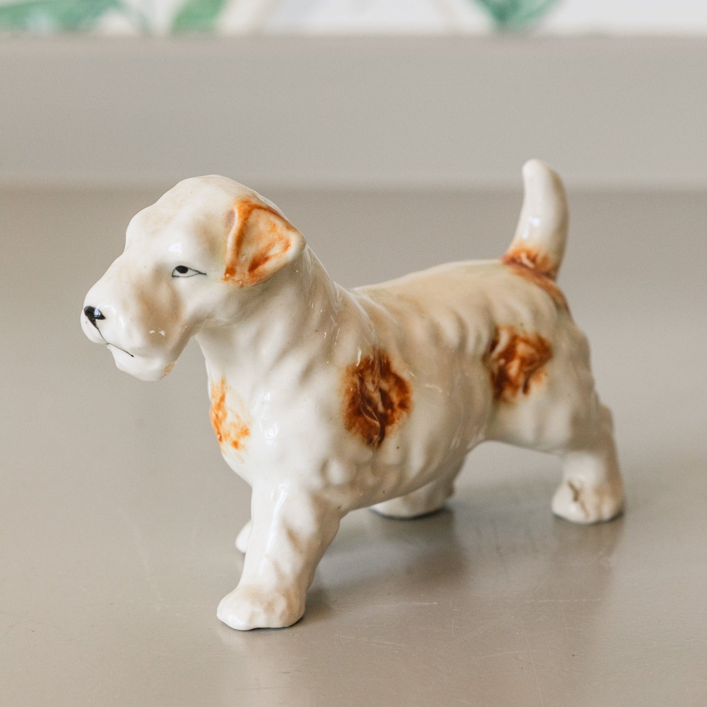 Small ceramic dog figurine on a neutral surface with a blurred background