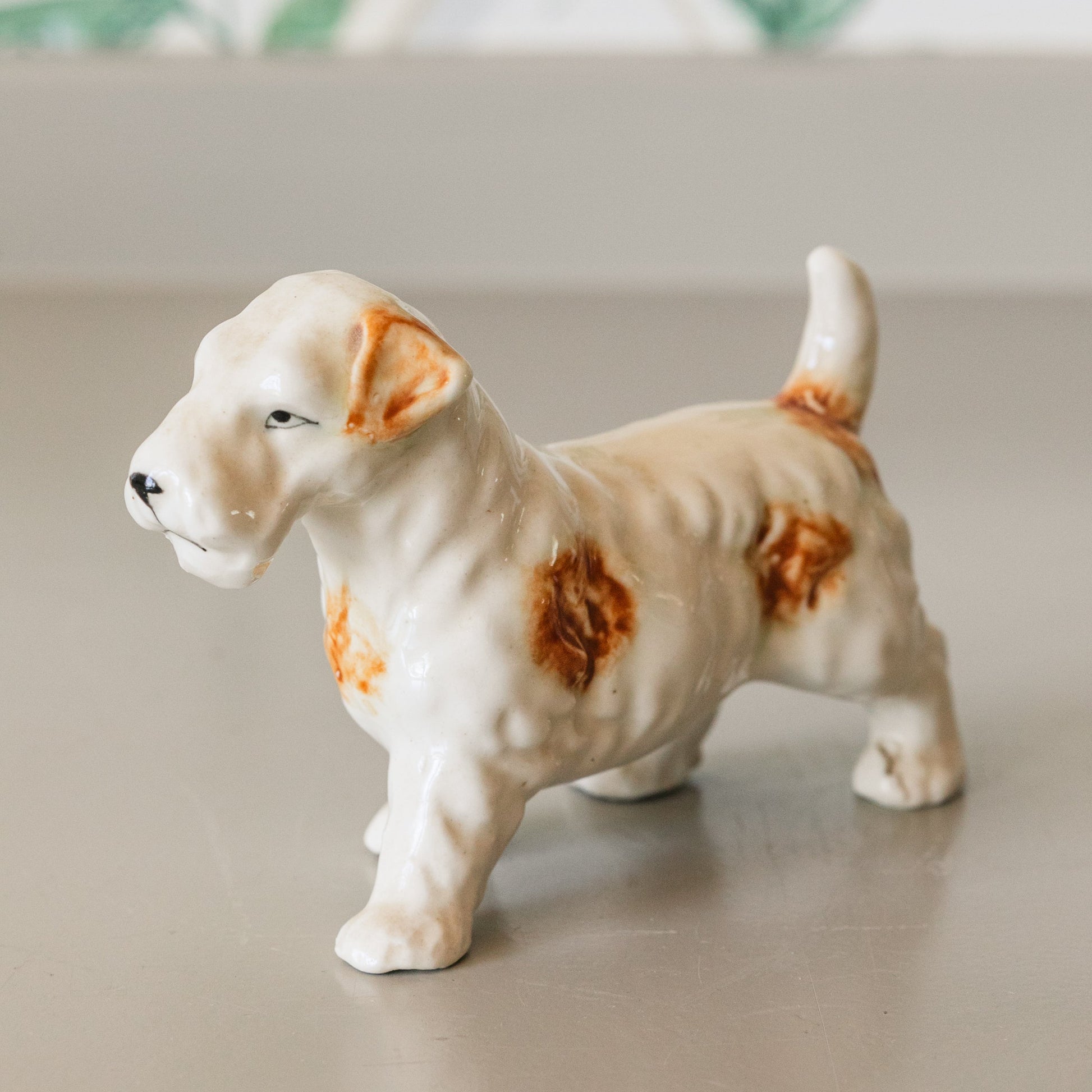 Small ceramic dog figurine on a neutral surface with a blurred background