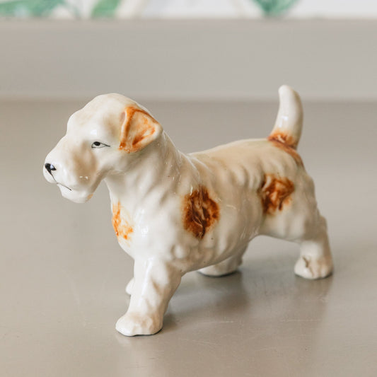 Small ceramic dog figurine on a neutral surface with a blurred background