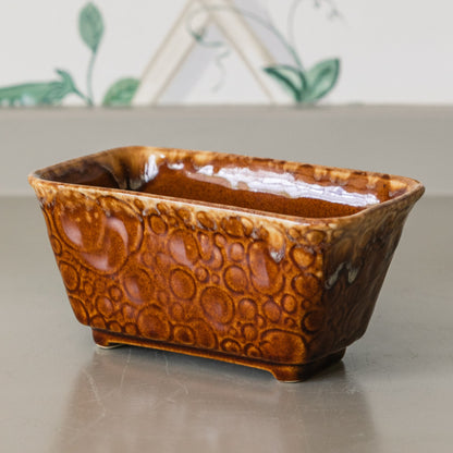 Brown ceramic loaf pan on a light surface with a decorative background