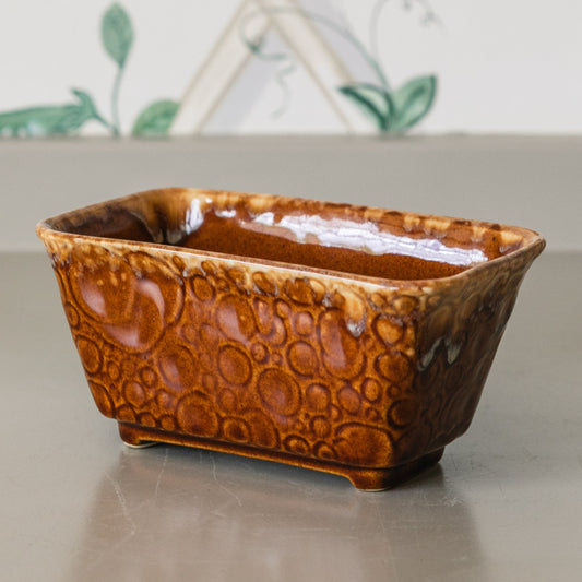 Brown ceramic loaf pan on a light surface with a decorative background